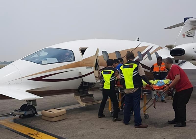 A medical team transferring a patient on a stretcher into an air ambulance on the runway
