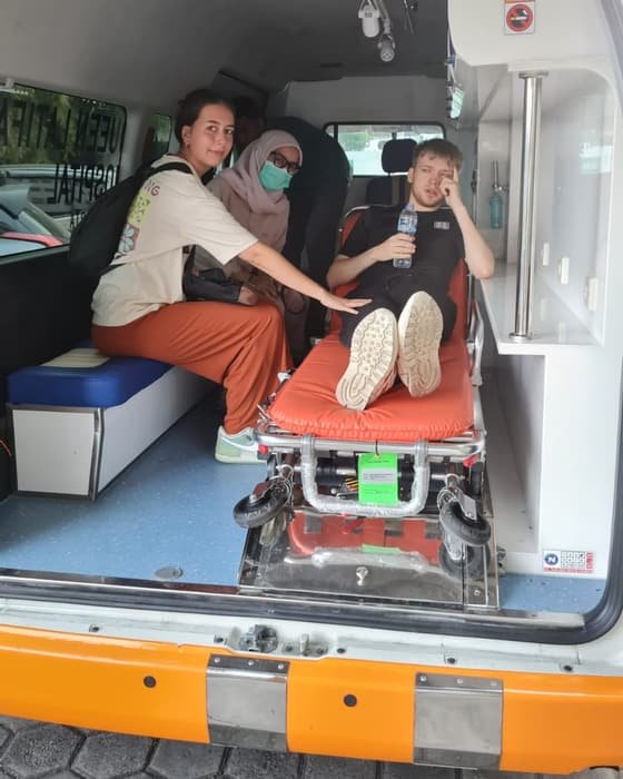 A patient on a stretcher inside a Mitra 911 ambulance, accompanied by a nurse and a companion