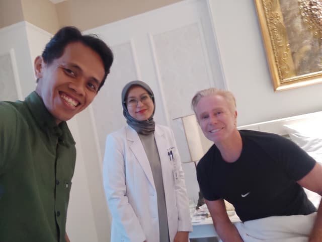 A Mitra 911 nurse and coordinator attending an international guest in his room